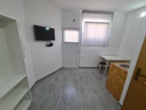 Dieses weiße Zimmer verfügt über eine Tür, einen Tisch und einen TV. in der Unterkunft Budget Apartment LeLo Centar2 in Osijek + 2 Fotos