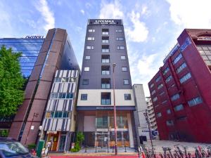 a tall building in the middle of two buildings at HOTEL LiVEMAX Fukuoka Tenjin West in Fukuoka