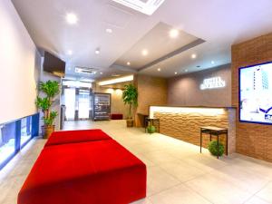 a lobby with a red bench and a television at HOTEL LiVEMAX Fukuoka Tenjin West in Fukuoka