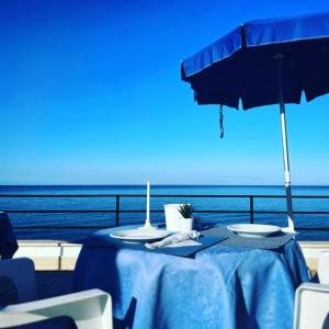 a table with a blue table cloth and an umbrella at Hotel La Scogliera in Cavi di Lavagna