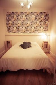 a bedroom with a white bed with a floral painting on the wall at Le T.Green in La Gorgue