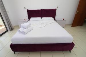 Una cama grande con sábanas blancas y toallas. en Bora Rooms, en Himare