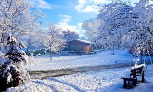 a snow covered park with a bench and a building at Chalet Vacanze Il Daino in Leonessa