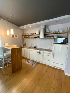 a kitchen with white cabinets and a wooden floor at Apartament Stella Maris in Puck