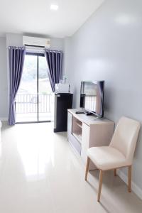 a white living room with a chair and a television at Order Residence in Ban Pa Muat