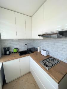 a kitchen with white cabinets and a stove top oven at AL-DOM Apartamenty Apartament IZI in Kołobrzeg