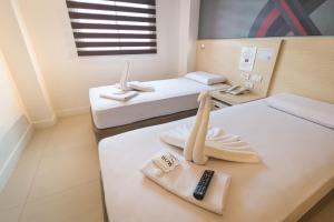 マニラにあるWow Budget Hotel Cubaoのベッド2台、リモコンが備わる客室です。