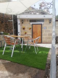 Casa cueva El perucho في غيمار: طاولة وكراسي على رقعة من العشب أمام المنزل