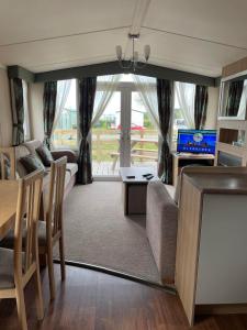 a living room with a couch and a table and a television at Swift bordeaux 24 in Dunoon +14 photos