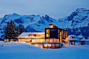 a building in the snow with mountains in the background at Berggasthaus Oberdorf in Wildhaus