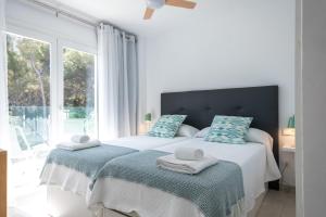 biała sypialnia z 2 łóżkami i oknem w obiekcie Sunny apartment 1B with balcony & pool in canyamel w mieście Capdepera +24 zdjęcia