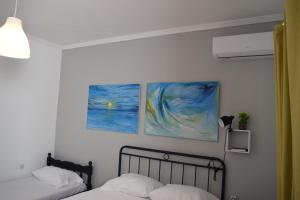 two beds in a bedroom with two paintings on the wall at Sunloft-Paros in Naousa