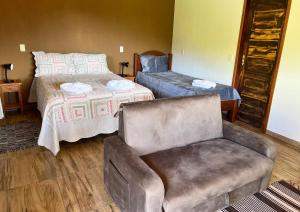 um quarto com um sofá, uma cama e uma cadeira em Pousada Barra Das Antas em Visconde de Mauá