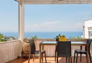 uma mesa e cadeiras numa varanda com vista para o oceano em Capri Town Apartments em Capri