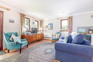 - un salon avec 2 chaises bleues et une télévision dans l'établissement The Old Mill Cottage - 10 Mins to St Andrews, à St Andrews