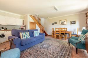 a living room with a blue couch and a kitchen at The Old Mill Cottage - 10 Mins to St Andrews in St. Andrews