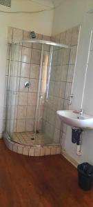 a shower with a glass door next to a sink at Open View Guest Inn in Kempton Park