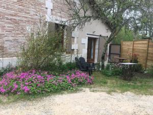 - un jardin avec des fleurs violettes, une table et des chaises dans l'établissement Maison Périgord vert piscine et spa, à La Roche-Chalais