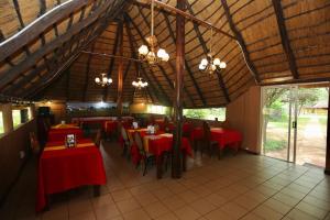 a restaurant with red tables and chairs and windows at Divundu Guest House in Divundu