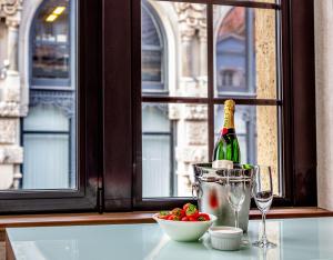 a bottle of champagne and a bowl of fruit and a glass at Hotel Grand City Wrocław in Wrocław