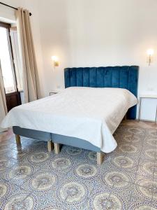 Schlafzimmer mit einem großen Bett mit blauem Kopfteil in der Unterkunft B&B Faraglione in Lipari