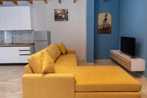 a living room with a yellow couch and a tv at Villa The Old Bakery in Qeparo