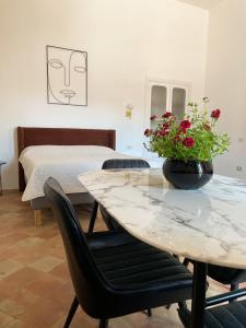 Cette chambre comprend une table, un lit et une table fleurie. dans l'établissement B&B Faraglione, à Lipari