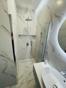 Baño blanco con lavabo y espejo en Apartamenty Plaza Tower, en Kielce