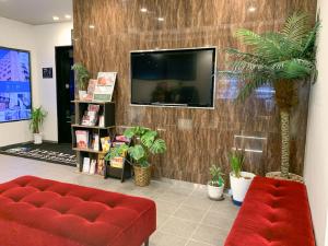 a living room with a red couch and a tv at HOTEL LiVEMAX Fukuyama Ekimae in Fukuyama