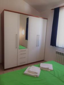 a bedroom with white cabinets and a green blanket at Apartments Barbara Gregovica in Pula
