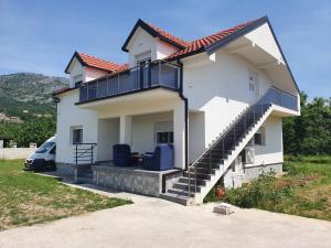 a white house with a balcony and a car at Murtovina Podgorica in Podgorica