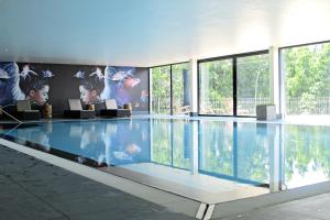 ein großer Pool in einem Gebäude mit Fenstern in der Unterkunft Van der Valk Naturresort Drewitz in Nossentiner Hütte