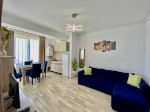 sala de estar con sofá azul y cocina en Vedere la mare apartament en Mamaia