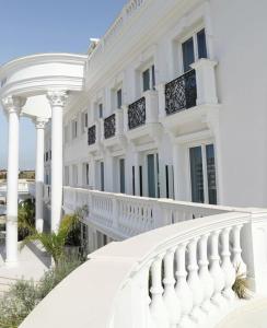 a white building with columns and a white balcony at Hotel Villa Pascucci in Durrës