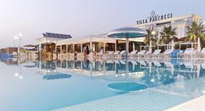 a swimming pool with white chairs and a hotel at Hotel Villa Pascucci in Durrës