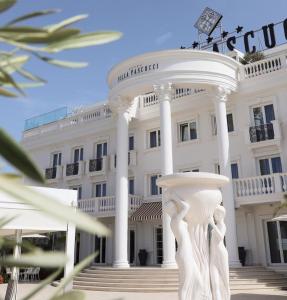 a white building with a statue in front of it at Hotel Villa Pascucci in Durrës