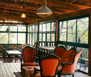 eine Veranda mit Stühlen, einem Tisch und Fenstern in der Unterkunft Mantur Parod by Selina in Parod