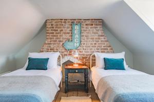 two beds in a attic room with a brick wall at Stillwater - Former fisherman's cottage, close to beach in Kent