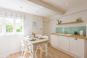 a kitchen with white cabinets and a table and chairs at Stillwater - Former fisherman's cottage, close to beach in Kent