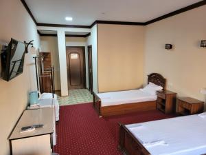 a hotel room with two beds and a television at MUFARSHOX in Bukhara