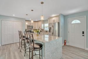 a kitchen with white cabinets and a island with bar stools at Private Cozy Sarasota Home home in Sarasota