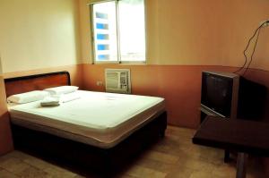 sypialnia z łóżkiem i telewizorem w obiekcie GV Hotel - Masbate w Masbate