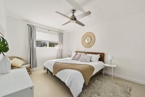 a white bedroom with a bed and a ceiling fan at The Guava Door - Cheerful Mid-Century - big yard, free parking in Austin