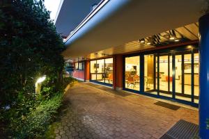 a building with glass doors and a sidewalk in front at Blue Relais Maggiore in Castelletto sopra Ticino