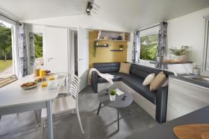 a living room and kitchen with a couch and a table at Le Domaine du Bois Coquet in La Douze