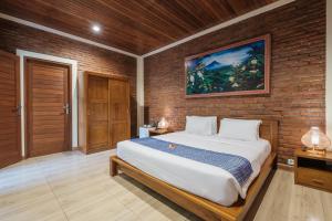 a bedroom with a bed and a brick wall at Dhiari Guest House in Ubud
