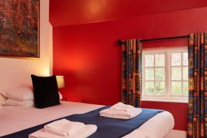 アシュボーンにあるFinest Retreats - The Farmhouseの赤いベッドルーム(ベッド2台、窓付)