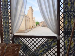 a view of a street from a balcony with curtains at "YOQUT HOUSE" guest house in the centre of ancient city in Khiva