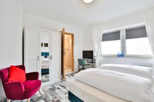 een slaapkamer met een bed en een rode stoel bij Hotel JUMAs in Bad Zwischenahn