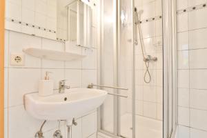 ein weißes Badezimmer mit Waschbecken und Dusche in der Unterkunft Hotel JUMAs in Bad Zwischenahn